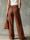Woman wearing beige wide leg linen pants with button fly closure and side pockets