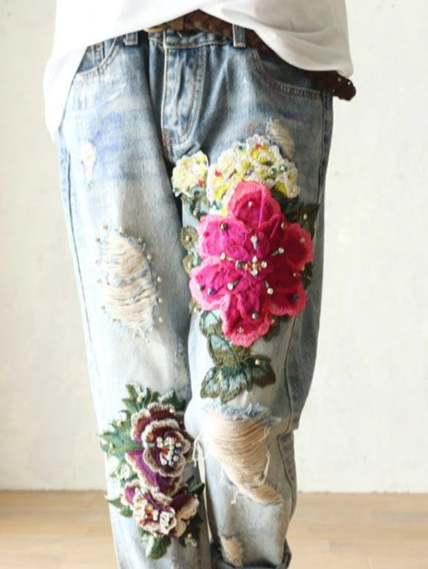 Vintage floral embroidered high-waist denim jeans with loose fit, button fly, and enzyme wash for stylish casual wear.