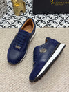 Close-up of embroidered detail on black leather loafers for men.