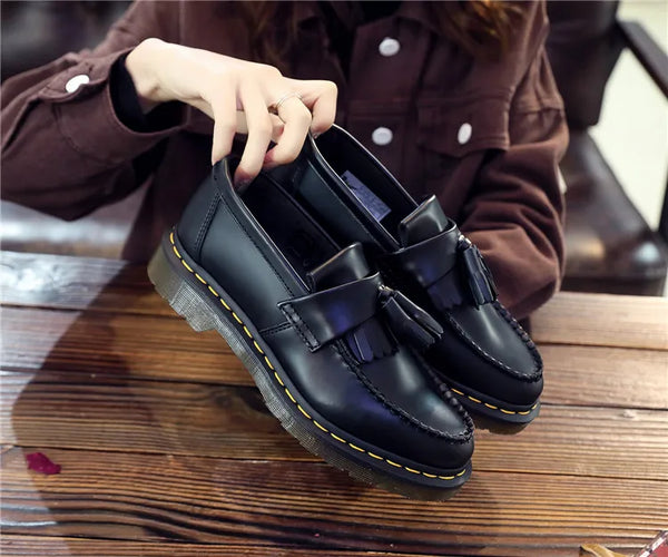 Black tassel loafers with a soft step on urban pavements.