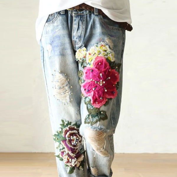 Vintage floral embroidered high-waist denim jeans with loose fit, button fly, and enzyme wash for stylish casual wear.