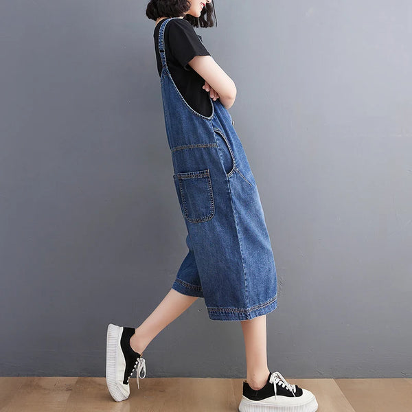 Front view of cotton-polyester blend denim suspender jumpsuit with loose silhouette and wide leg cut