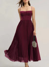 Sophisticated black dress with suspender straps, pleated texture, and slim-fit silhouette