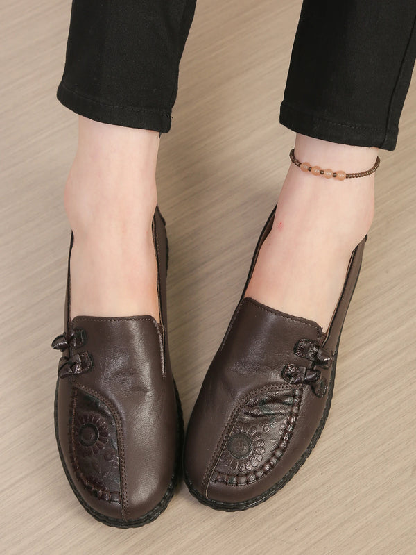 Women's brown leather loafers featuring floral embellishment and slip-on convenience