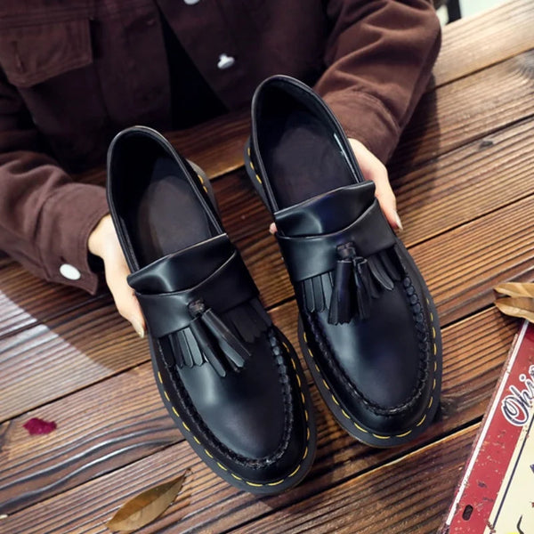 Black tassel loafers made of supple split leather for comfort and style.