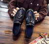Black tassel loafers with a classic British design aesthetic.