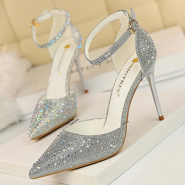 Side view of sparkly rhinestone pumps with thin high heels and buckle strap closure