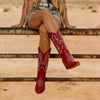 Detailed close-up of artisan embroidery stitching on brown leather knee-high western boots