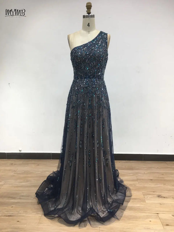 Full-length view of the elegant one-shoulder beaded gown in a grand ballroom setting.