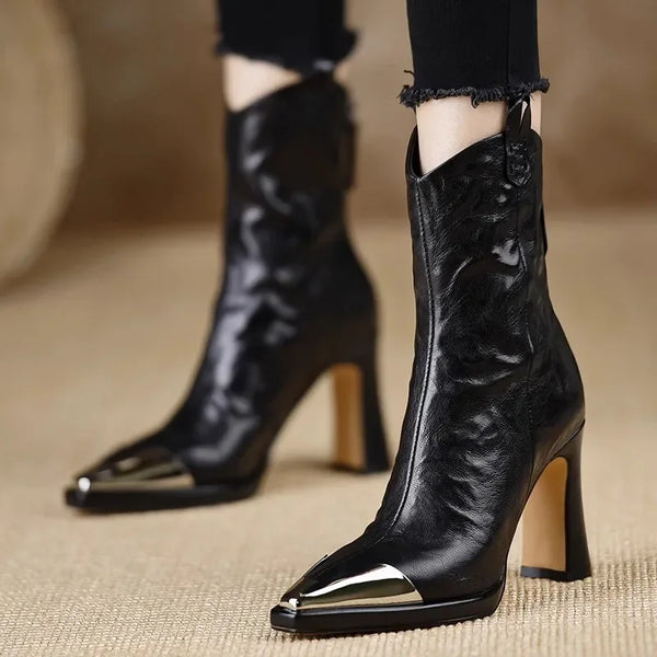 Black patent leather ankle boots with square toe and high block heel on white background