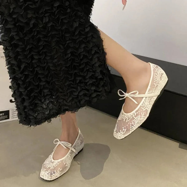 Close-up of embroidered ballet flats showing intricate bow detail and soft supple material