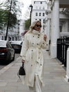 Timeless cream trench coat with double-breasted closure and tie belt on white background