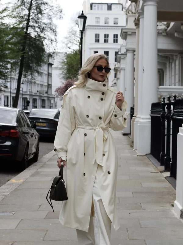 Timeless cream trench coat with double-breasted closure and tie belt on white background