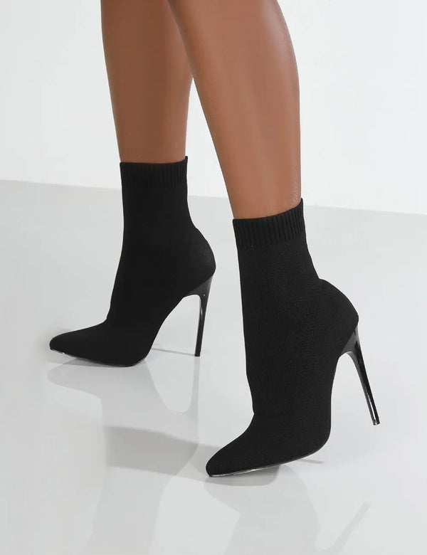 Black knitted sock ankle boots with super high thin stiletto heel on white background