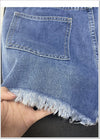 Button fly shorts in cotton blend with edgy rips and hand-finished fringe details