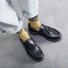 Close-up of black tassel loafers with a polished leather finish.