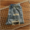 Model sitting by a campfire in Rebel Spirit Distressed Jeans, embodying outdoor spirit.
