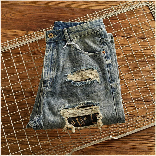 Model sitting by a campfire in Rebel Spirit Distressed Jeans, embodying outdoor spirit.