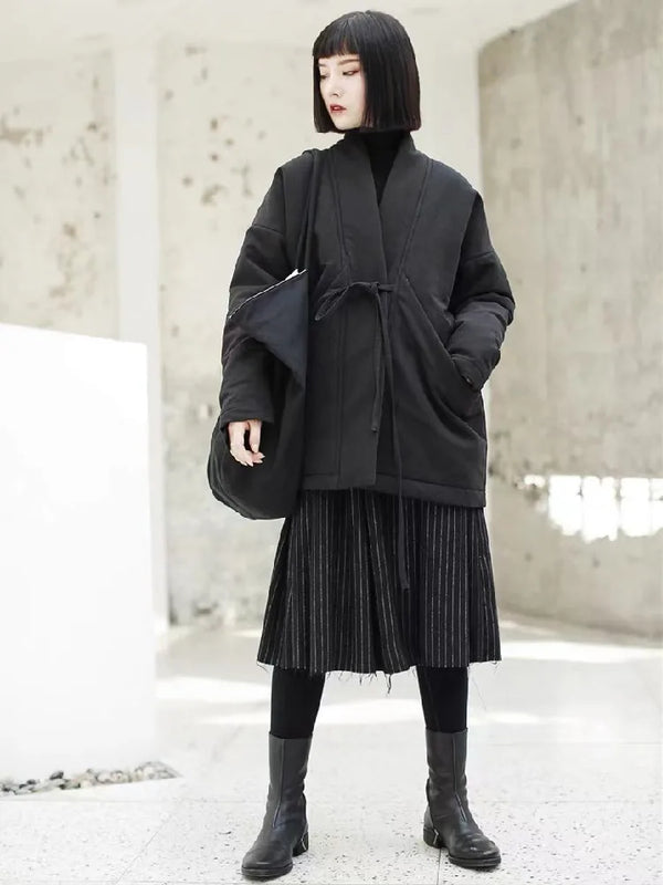 Woman wearing oversized cotton padded winter jacket with adjustable waist belt and hood