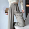 Woman wearing high-waist wide leg trousers with tucked blouse showing elongating silhouette and relaxed fit
