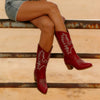 Woman wearing embroidered western boots with chunky heel paired with denim jeans and flowing skirt