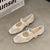 Beige square-toe ballet flats with delicate bow detail and embroidered accents on white background