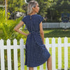 Woman wearing black and white polka dot midi dress with sash belt