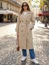 Woman wearing x-long double-breasted trench coat with adjustable sash belt